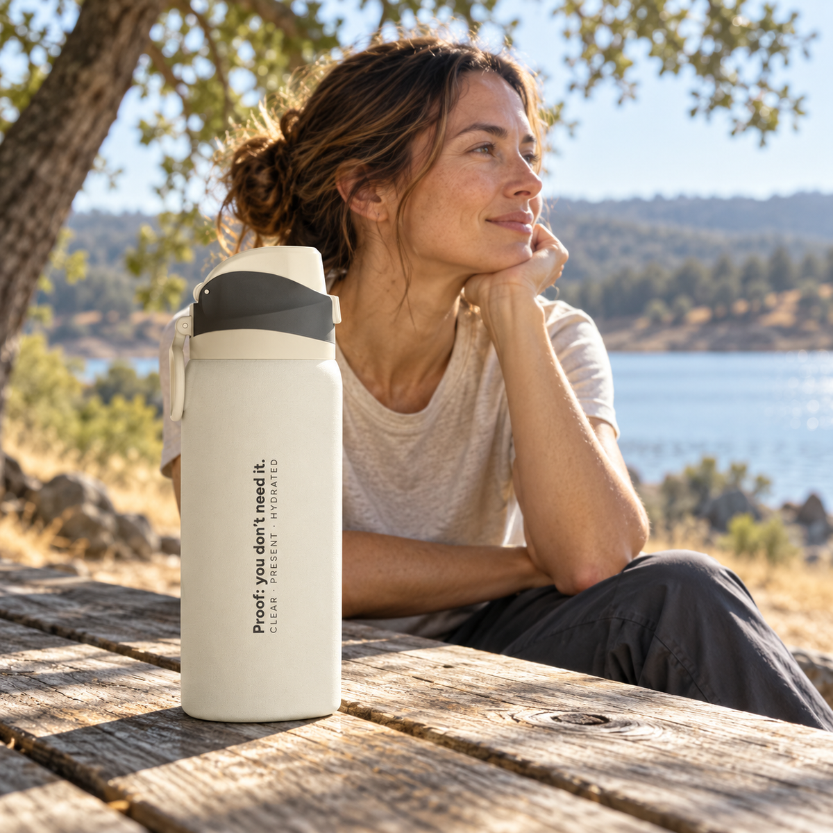 Ivory Clear Path bottle on a wooden picnic table beside a seated person, with a lake in the background.