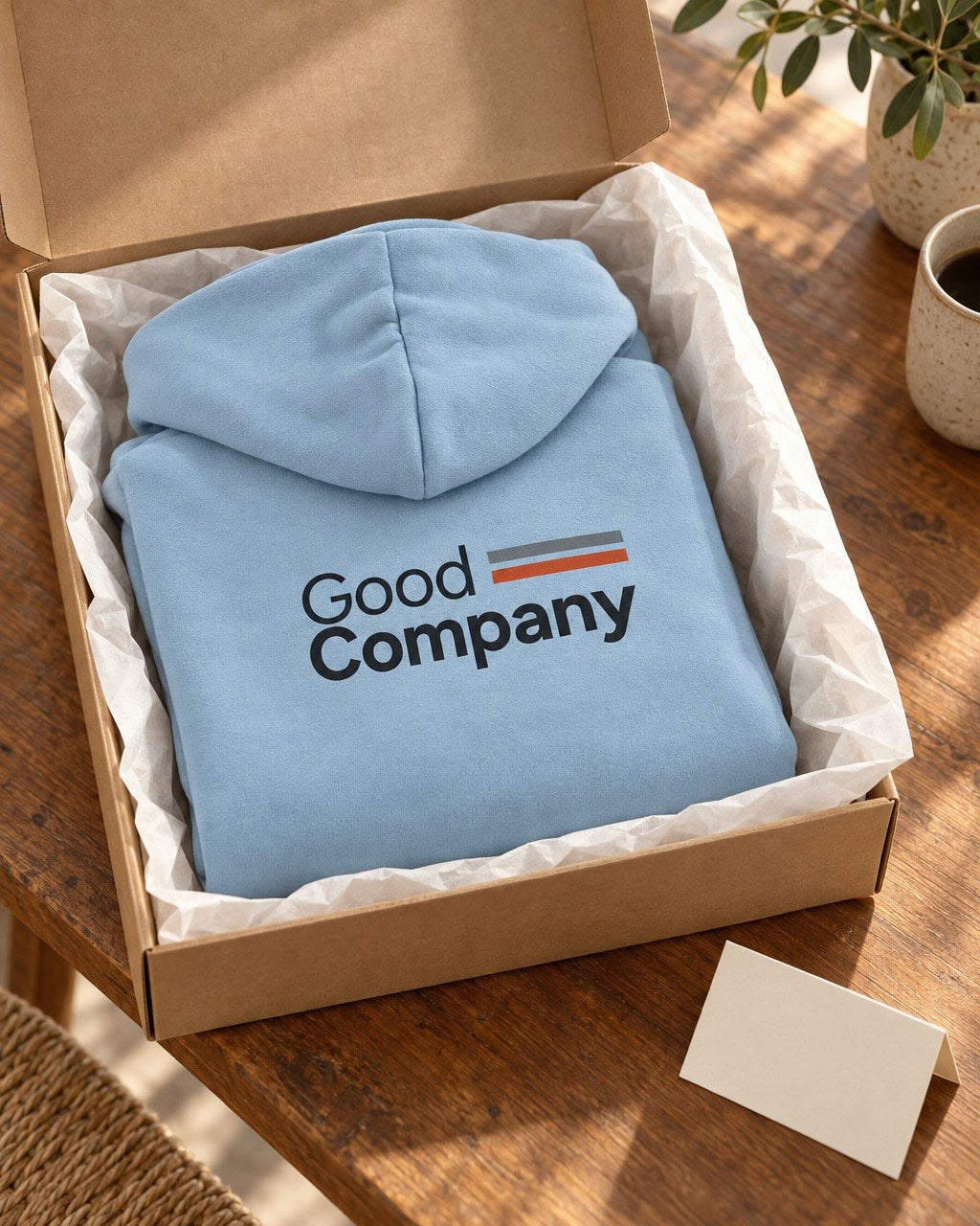 Light blue Good Company hoodie folded in a kraft gift box