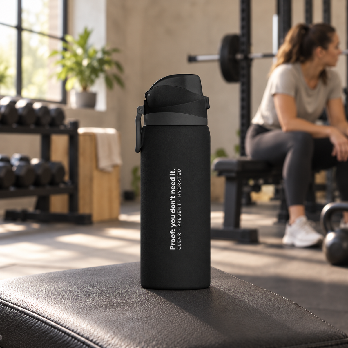 Black Clear Path bottle on a padded gym bench, with weights and a seated person in the background.